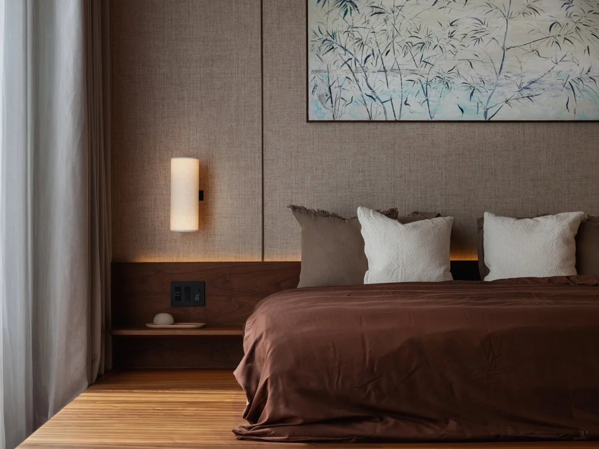 Nanpeidai bedroom detail: upholstered wall, timber bedside and wall light