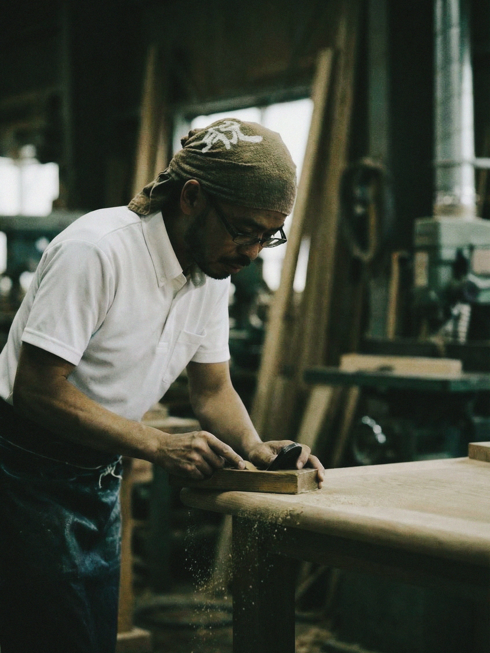 A craftsman planing a tabletop by hand in the workshop